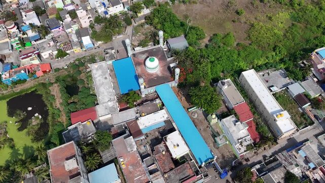 Wide aerial panorama of Kovalam Dargah featuring its mosque complex, surrounding village, tropical greenery, ponds, and urban landscape. spiritual and architectural character of coastal Kovalam.
