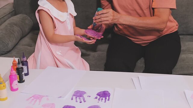 A young Asian toddler concentrates on her drawing activity at home, developing fine motor skills and learning as part of her early childhood education.