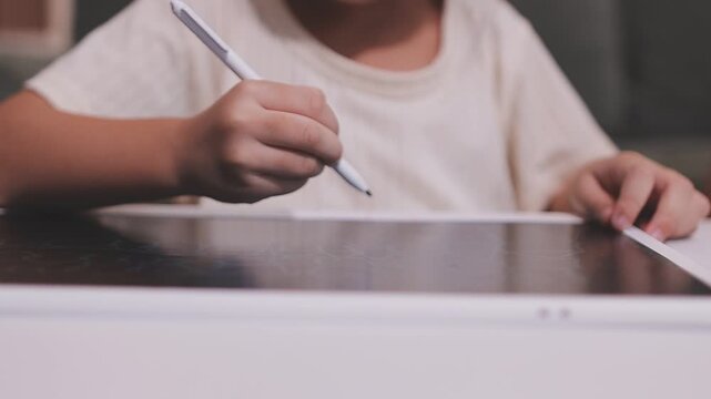 A young Asian toddler concentrates on her drawing activity at home, developing fine motor skills and learning as part of her early childhood education.