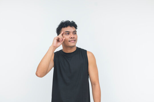A young Southeast Asian man in a black tank top gestures thoughtfully while looking away, expressing a positive idea or solution.