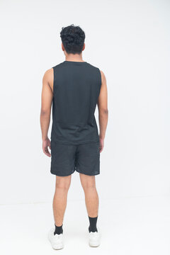 A young man stands facing away from the camera in athletic clothing, showcasing the back view of a sports outfit.