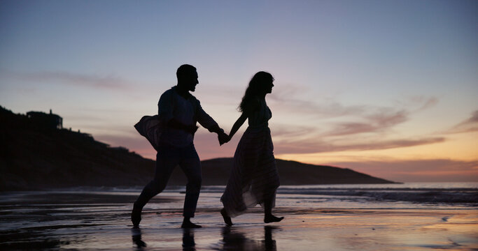 Couple, walking and holding hands at beach with smile, travel and romantic date on holiday. Sunset, people and journey on seashore with space, commitment and tropical vacation for adventure getaway