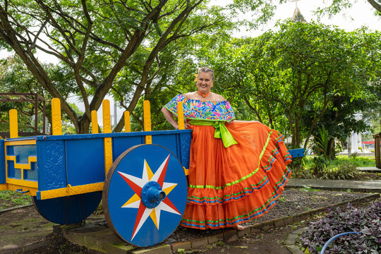Smiling woman posing with traditional colorful costa rican oxcart