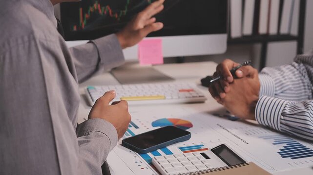 Two busy business men investors doing financial trading market data analysis. Male advisor and analyst consulting about stock exchange investing pointing at chart on laptop computer working in office.