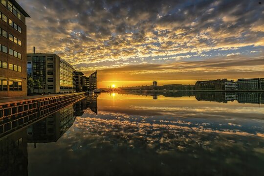 Farbintensiver Sonnenuntergang spiegelt sich im Wasser zwischen modernen Geb&auml;uden, Kopenhagen, D&auml;nemark