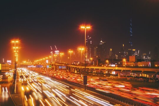 Panorama Dubai heavy night night traffic on Sheikh Zayed Road after work rush hour traffic. Light trails lead to the Burj Khalifa and Downtown Dubai cityscape at night landmarks skyline