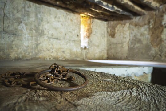 Close-up of authentic iron chains and shackles display in underground slave chamber in Mkunazini, Zanzibar. Somber historic artifact in a dimly lit Stone Town dungeon