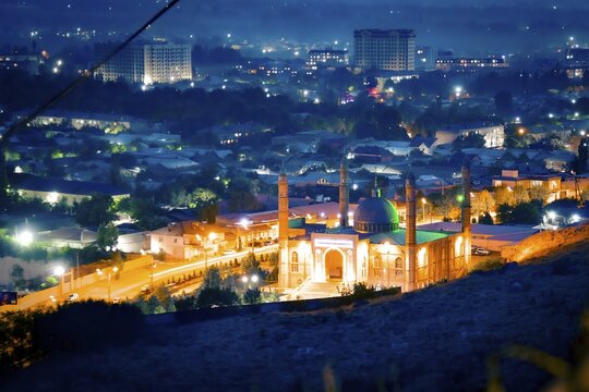 Osh central mosque kyrgyzstan timelapse day to night cityscape glowing green dome minarets urban lights residential district mountain backdrop dusk transition. Sulaiman - Too mountain