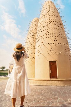Doha, Qatar - 15th january, 2026: Woman traveler tourist taking picture of Katara pigeon towers in Doha showcasing traditional Qatari architecture desert climate design cultural heritage landmark