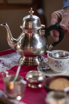 Hand touches handle of an old teapot, traditional English afternoon tea, Chapslee Hotel, former summer residence of Raja of Kapurthal, Elysium Hill, Lakkar Bazar, Shimla, Himachal Pradesh, North India, India