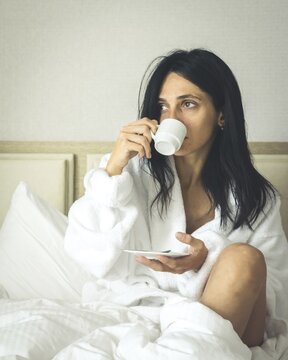 Caucasian Woman drinks morning espresso in cosy bed. Batumi. Georgia