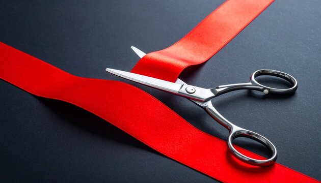 Silver scissors cutting red ribbon symbolizing inauguration ceremony opening