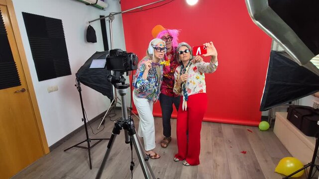 Senior friends in funny costumes taking selfies in a studio