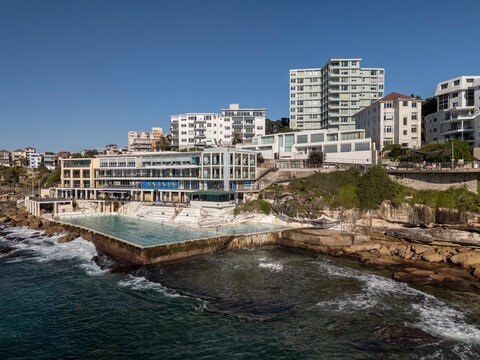 Bondi Beach on beautiful sunny day looking  over water to Icebergs pool, skyline and beachside architecture.