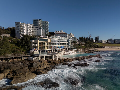 Bondi Beach on beautiful sunny day with blue sky looking to Icebergs pool, skyline and beachside architecture.