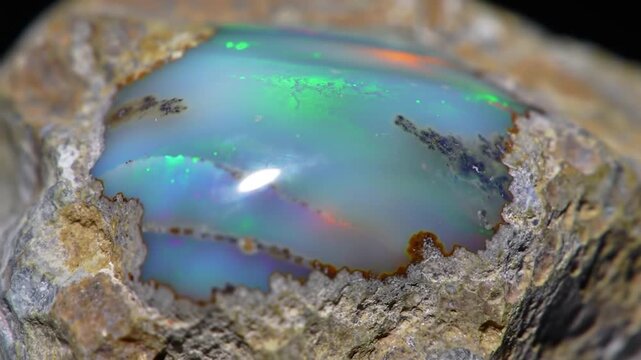 Iridescent opal gemstone embedded in natural host rock.
