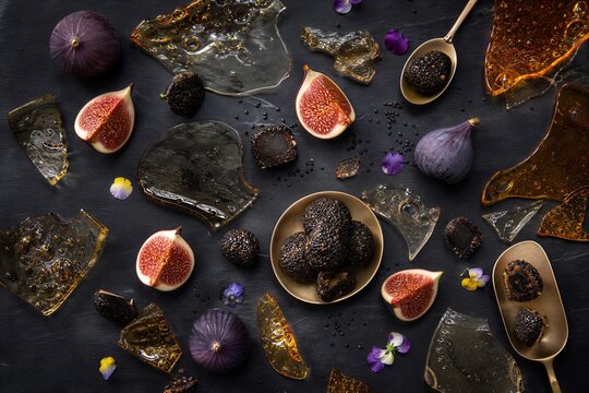 Halloween dessert board with fresh fig and black sesame truffle on dark slate. Artistic composition with sugar glass shard and edible flower for luxury sweet treat concept