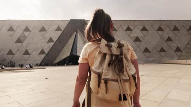 Caucasian woman tourist visitor walking towards entrance of the Grand Egyptian Museum in Giza