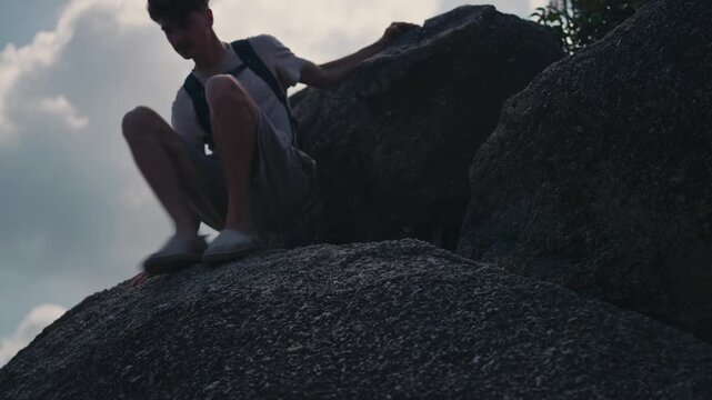 Young hiker climbing down large granite rocks in Koh Phangan