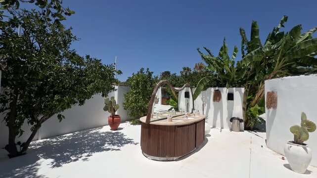 Sunny courtyard path lined with trees white cabanas and an outdoor vanity at a beach club resort in Cesme Turkey