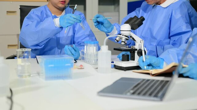 Focused scientists in PPE work together in a modern lab, examining samples and recording critical data for breakthrough research.
