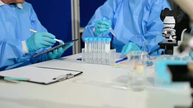 Focused scientists in PPE work together in a modern lab, examining samples and recording critical data for breakthrough research.