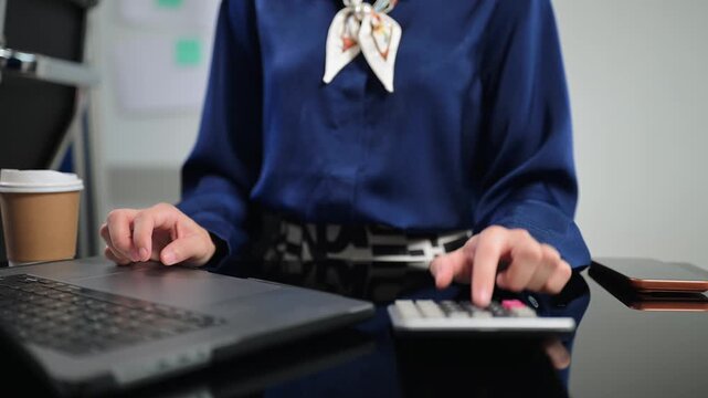 Women counting coins on calculator taking from the piggy bank. hand holding pen working on calculator to calculate on desk about cost at office.