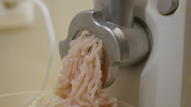 Minced meat comes out of the meat grinder close up