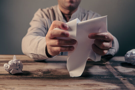Man writing on paper with crumpled paper ball in his hand