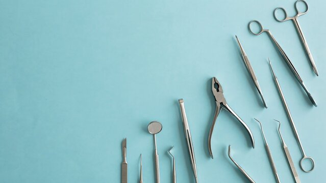 Set of assorted surgical steel dental instruments on a blue background