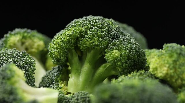 Pile of chopped broccoli florets slowly rotating on a black background