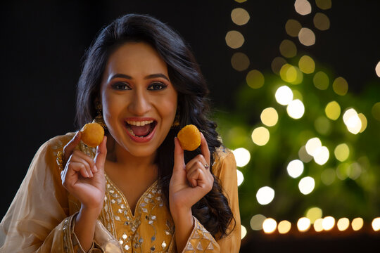 Woman smiling with ladoos in her hands on the occasion of Diwali