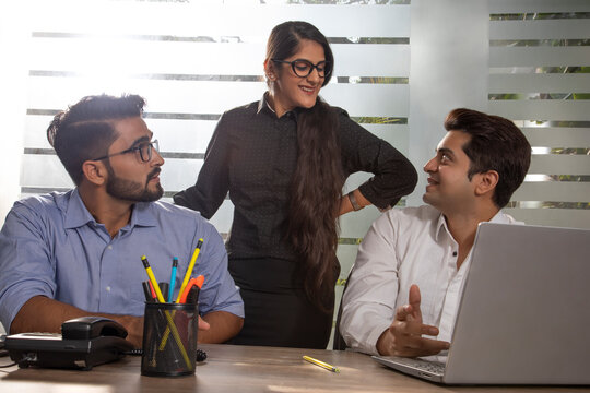 A YOUNG WOMAN EXECUTIVE DISCUSSING WORK WITH HER COLLEAGUES