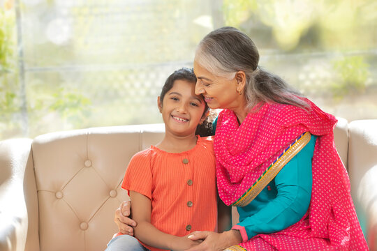 Grand mother holds her grand daughter as the grand daughter looks in to the camera