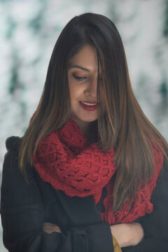 A WOMAN IN WINTER CLOTHES WITH FOLDED ARMS STANDING AND LOOKING DOWN