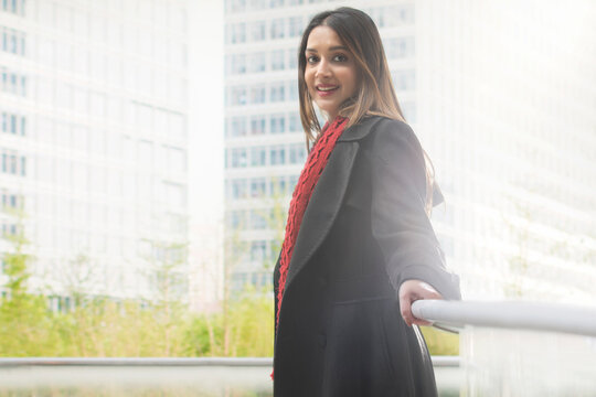 A CONFIDENT YOUNG WOMAN STANDING AND SMILING AT CAMERA
