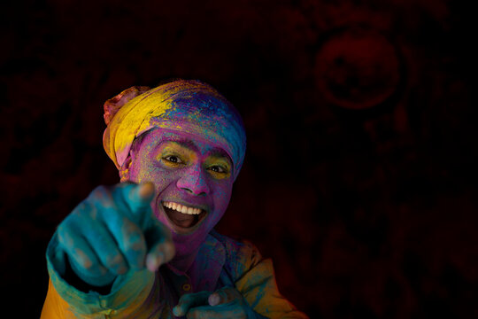 Man in turban smiling while dancing in excitement on Holi with gulal on his face