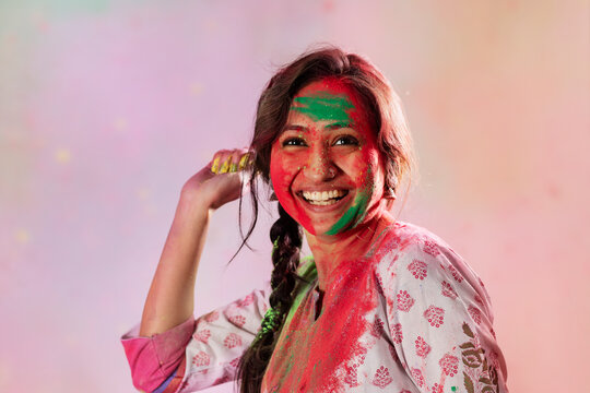 Woman with gulal on her face throwing colors in a playful manner