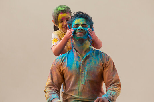 Little girl putting color on her father's face on Holi