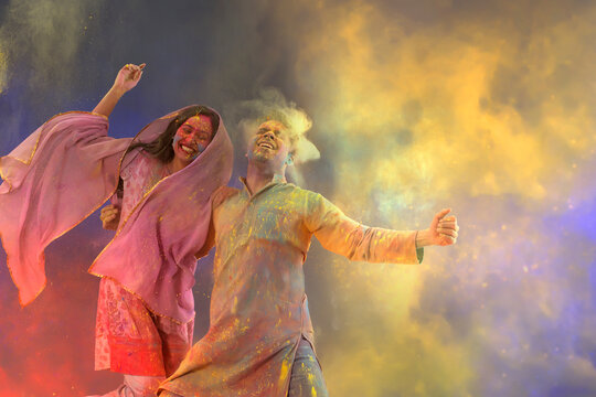 Husband and wife dancing while celebrating Holi with dry colors