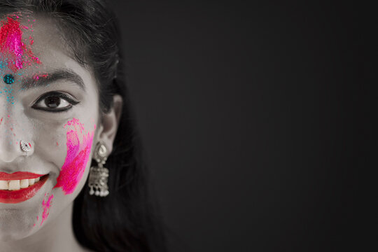 CLOSE SHOT OF A YOUNG WOMAN WITH HOLI COLOURS ON HER FACE 