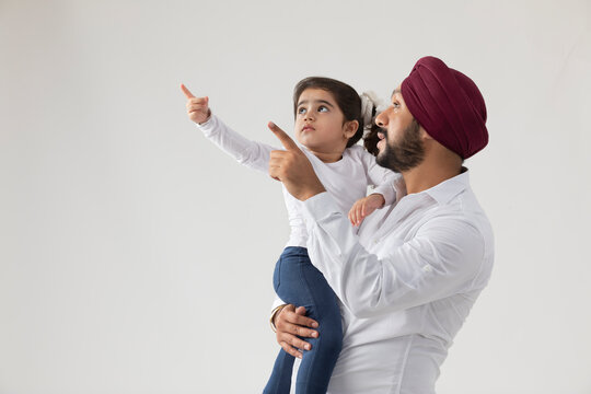 A SIKH FATHER AND DAUGHTER OBSERVING THINGS AROUND