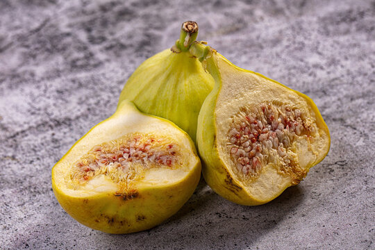 Fresh yellow figs sliced open on textured gray surface