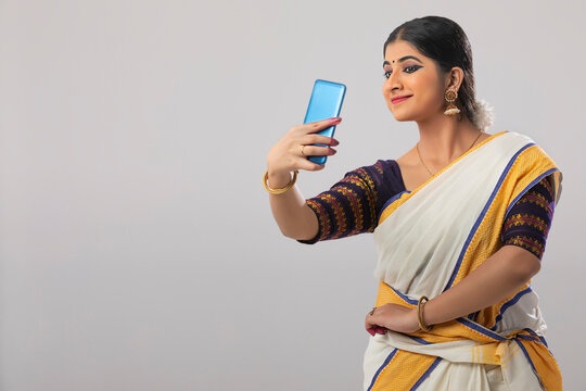 Woman smiling while clicking a selfie on her phone