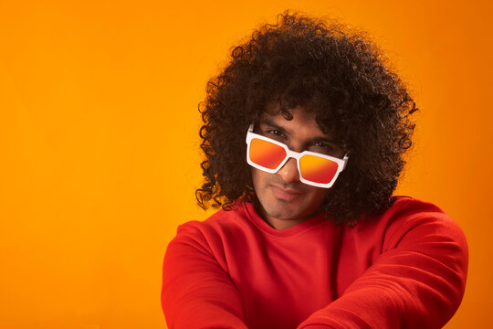 A YOUNG MAN WITH CURLY HAIR SERIOUSLY LOOKING AT CAMERA