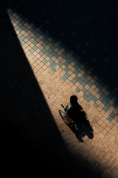 Overhead silhouette of a man in a wheelchair sitting in the shadows