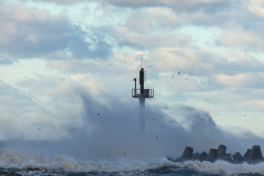 Waves crashing against a tall beacon on a breakwater, Klaipeda, Lithuania