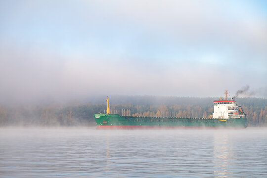 View into land of a Cargo ship sailing along the shoreline in the morning fog, Klaipeda, Lithuania