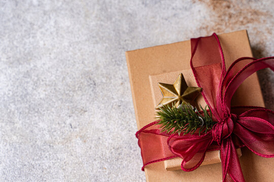 Close-up overhead view of two Gift boxes decorated with a fir sprig and star ornament and red ribbon tied in a bow