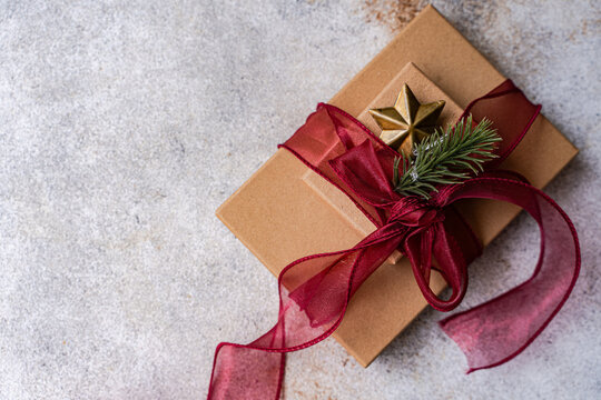 Close-up overhead view of two Gift boxes decorated with a fir sprig and star ornament and red ribbon tied in a bow